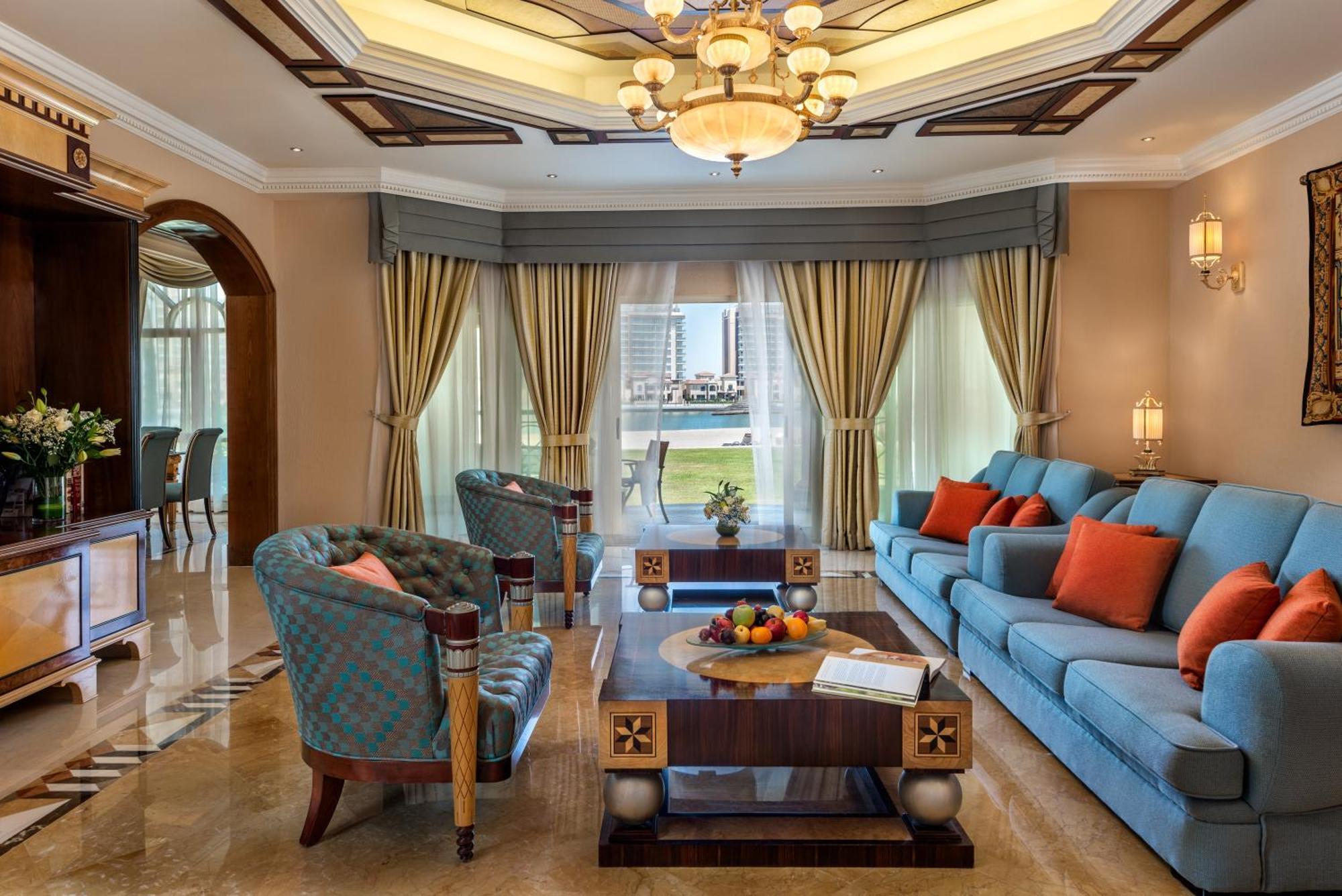 Al Raha Beach Resort & Spa Abu Dhabi Bagian luar foto The photo depicts an elegantly designed living room with a sophisticated atmosphere. It features a large, light blue sofa adorned with orange and blue cushions. There are two stylish armchairs nearby with a unique pattern. In the center, a coffee tab