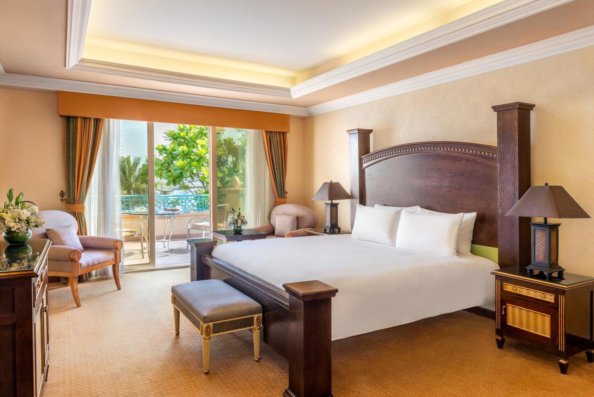 Al Raha Beach Resort & Spa Abu Dhabi Bagian luar foto The photo shows a well-appointed hotel bedroom. It features a large bed with white bedding, flanked by bedside tables with lamps. The room has light-colored walls and a warm-toned carpet. There is a comfortable seating area with a chair and a small t